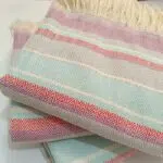 Lomyna LOCO towels in blue, red, and cotton tones arranged neatly in a stacked display.