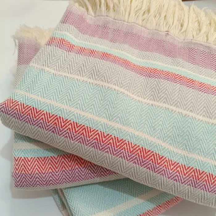 Lomyna LOCO towels in blue, red, and cotton tones arranged neatly in a stacked display.