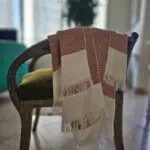 Lomyna LOVE orange towel with diamond weave pattern placed on the arm of a chair.