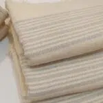 Folded LOCO hand-woven cotton hammam towel in natural cotton with grey linear stripe design