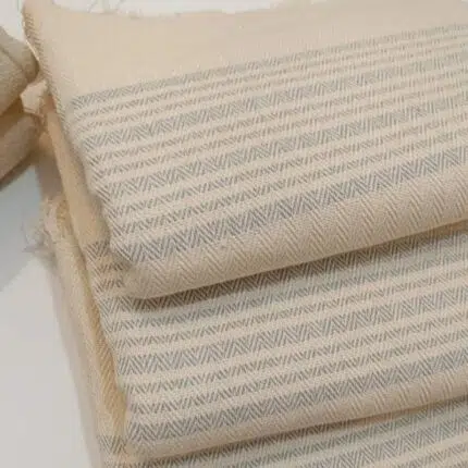 Folded LOCO hand-woven cotton hammam towel in natural cotton with grey linear stripe design