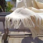 LOCO Hand-Woven Hammam Towel in its natural, unbleached cotton color, displayed in sunlight, showcasing Natural Purity, Ultra weave, and the positive energy of Timeless Luxury for spa/travel use.