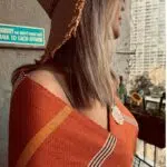 A woman looking into the distance wearing Lomyna LOVE maroon towel with mustard stripes.