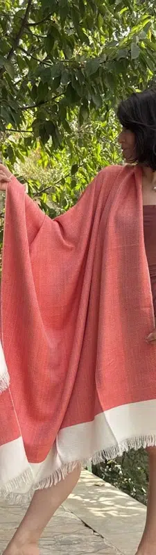 Woman displaying a red LOVE hand-woven viscose wrap with a white border in a natural outdoor setting