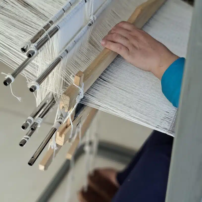Hand-Woven Textiles | From Loom to Life 1 Artisan weaving a hand-woven natural cotton textile on a traditional wooden loom